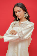 Woman wearing a white embroidered blouse against a red background