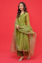Woman in a green traditional outfit with a dupatta against a red background