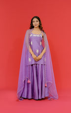 Woman wearing a purple traditional outfit with a red background
