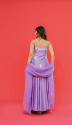 Woman wearing a purple dress with floral details on a red background