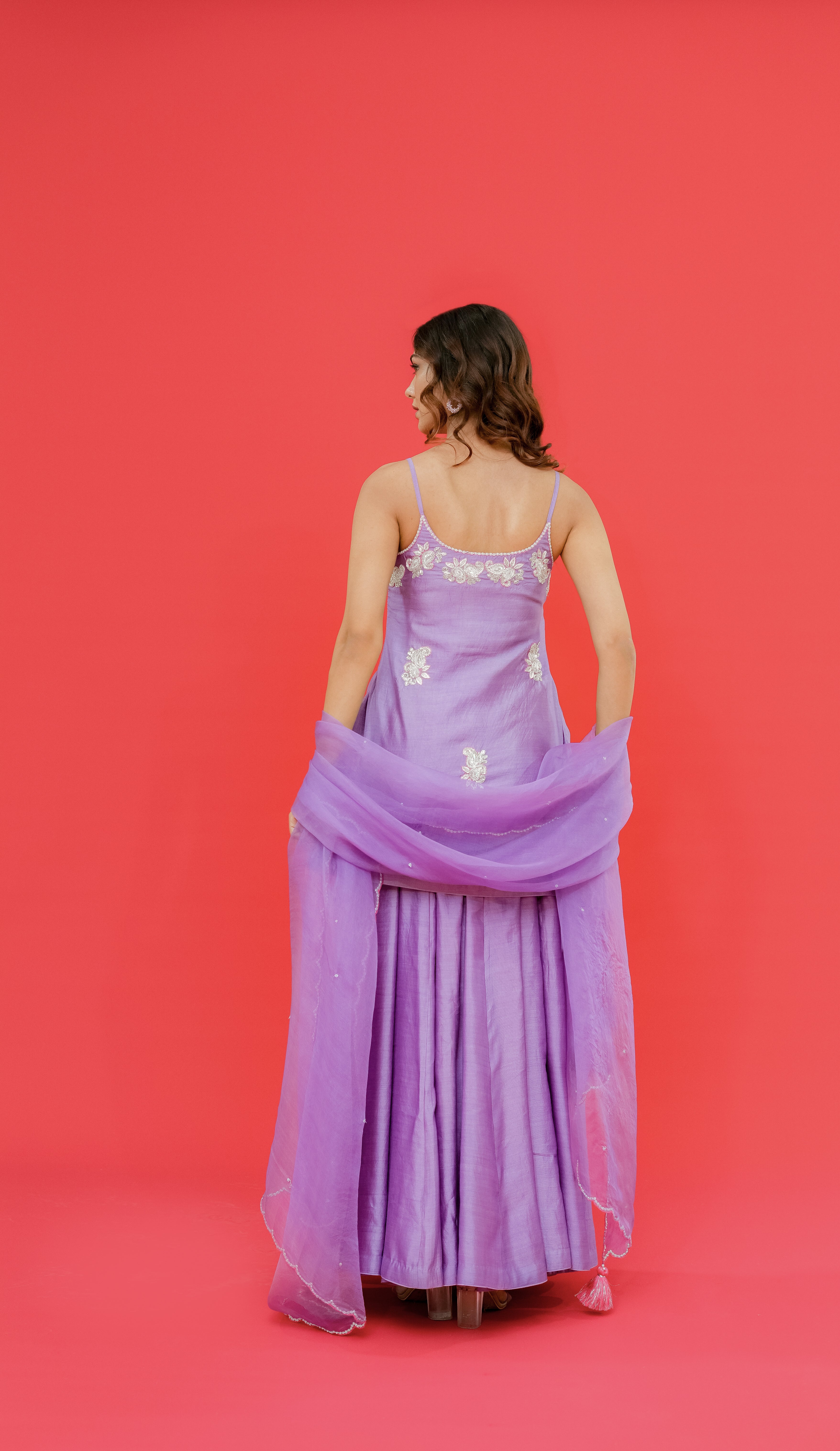 Woman wearing a purple dress with floral details on a red background