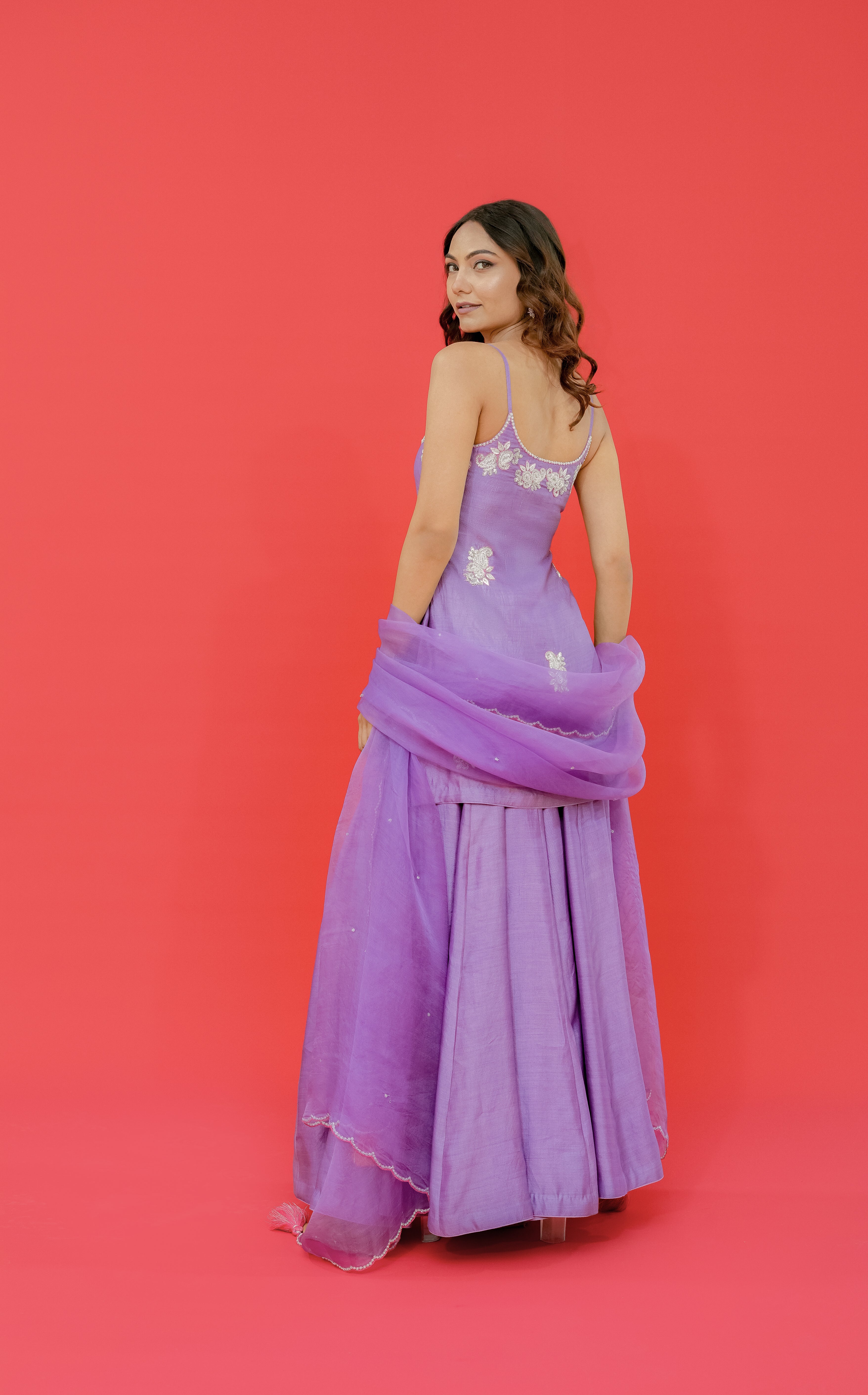 Woman in a purple gown with floral details on a red background