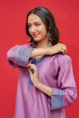 Woman wearing a purple dress with colorful embellishments against a red background