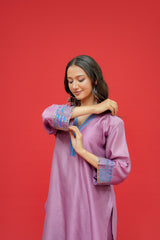 Woman wearing a purple dress with blue embroidery against a red background