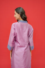 Woman wearing a pink traditional outfit with blue embroidery on a red background