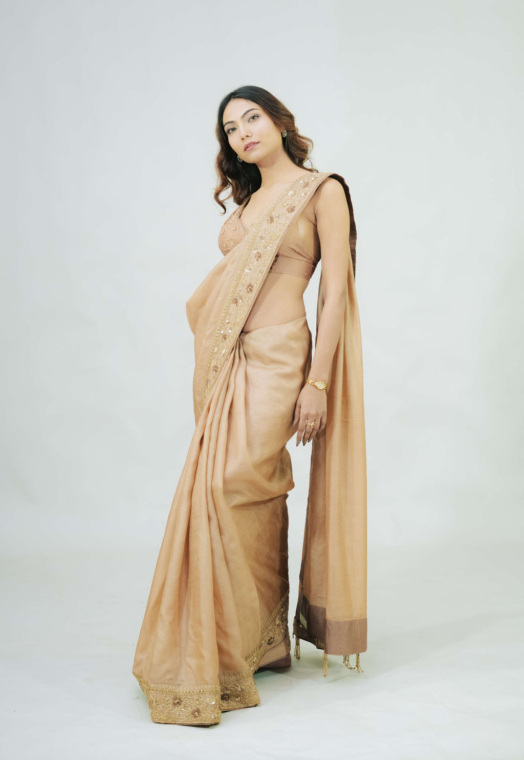 Woman wearing a beige saree with a white background