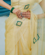 Yellow saree with green embellishments held by a person
