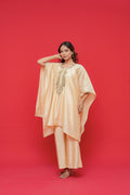 Woman wearing a peach-colored outfit with gold embroidery against a red background