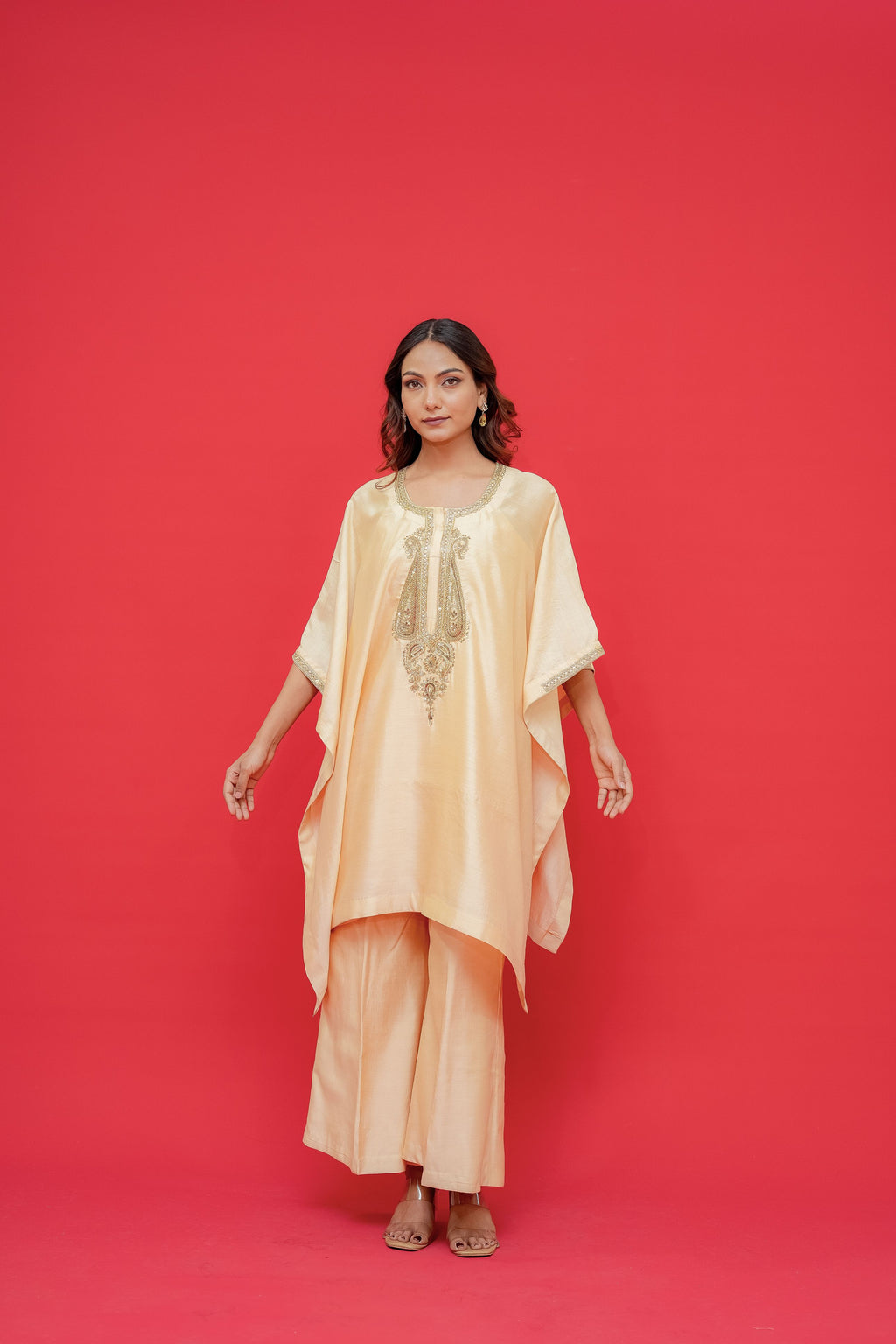 Woman wearing a peach-colored outfit with embroidery against a red background Kaftan with Fabric chiniya silk Hand Embroidery
