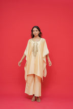 Woman wearing a peach-colored outfit with embroidery against a red background Kaftan with Fabric chiniya silk Hand Embroidery