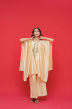 Woman wearing a peach-colored outfit with gold embroidery against a red background