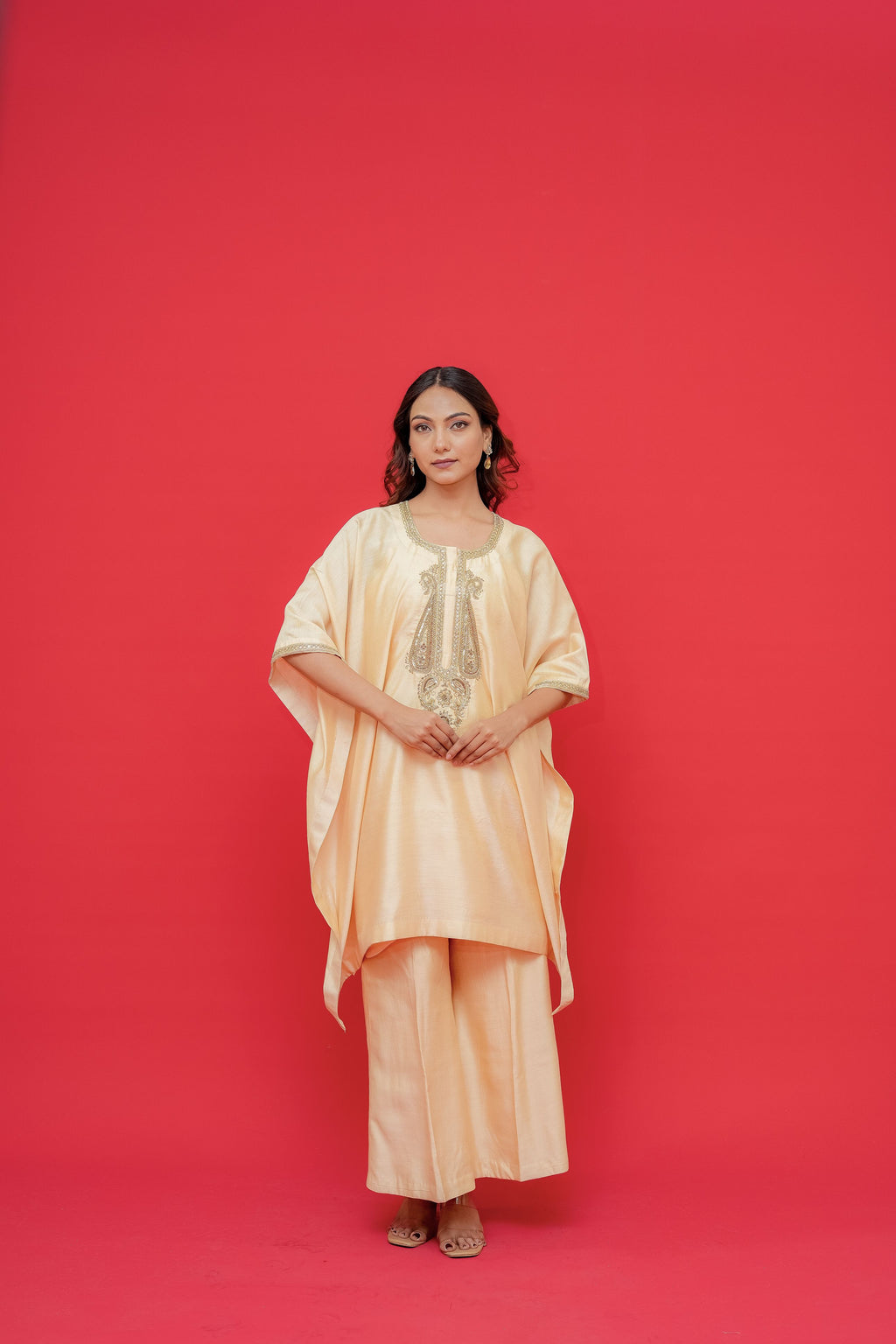 Woman wearing a peach-colored outfit against a red background