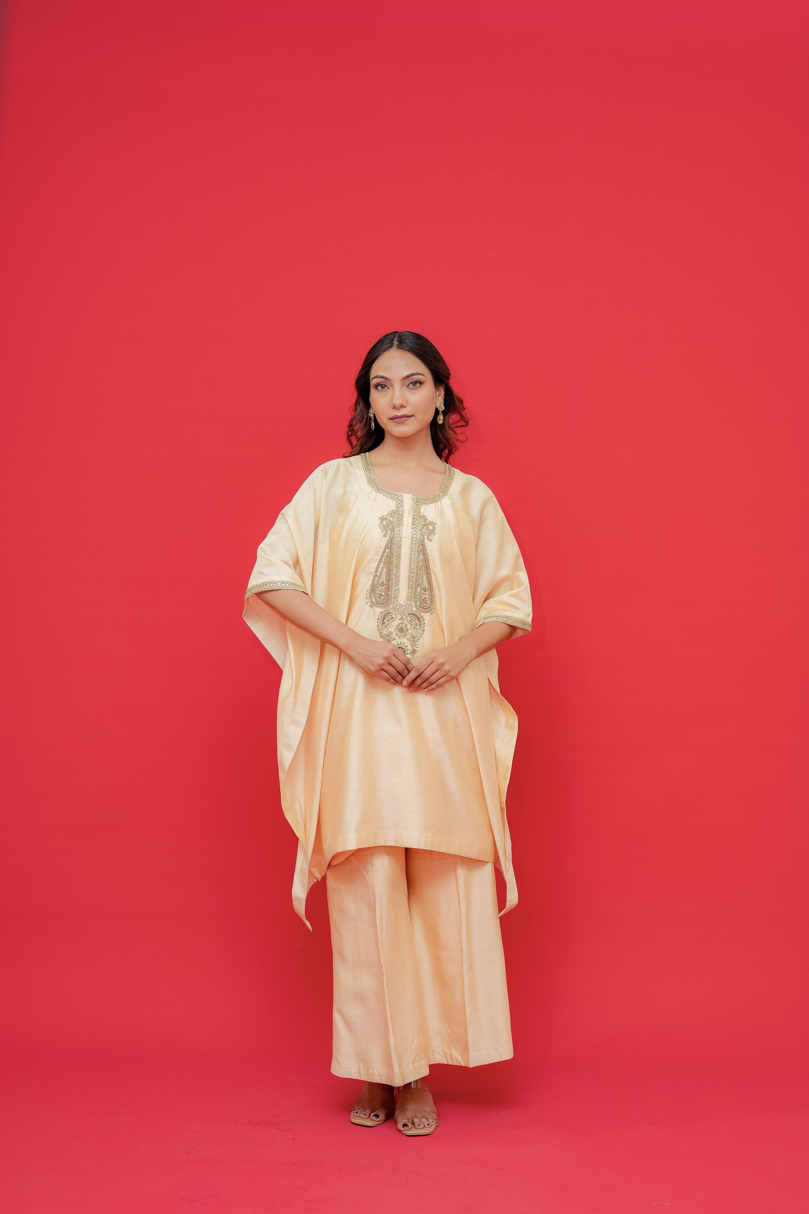 Woman wearing a peach-colored outfit against a red background