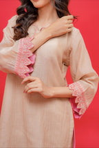 Woman wearing a beige dress with pink ruffled sleeves against a red background