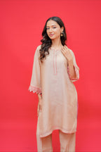 Beige embroidered straight kurta with matching palazzo pants featuring pink lace cuff detailing for women.