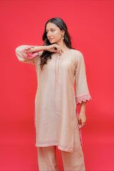 Woman wearing a light pink kurta with lace sleeves against a red background