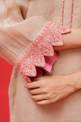 Close-up of a person wearing a pink embroidered sleeve with a red background