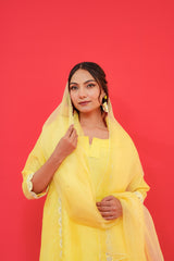 Woman wearing a yellow outfit with a matching dupatta against a red background