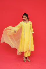 Woman in a yellow outfit with a sheer dupatta against a red background