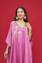 Woman wearing a pink dress with gold embroidery against a red background