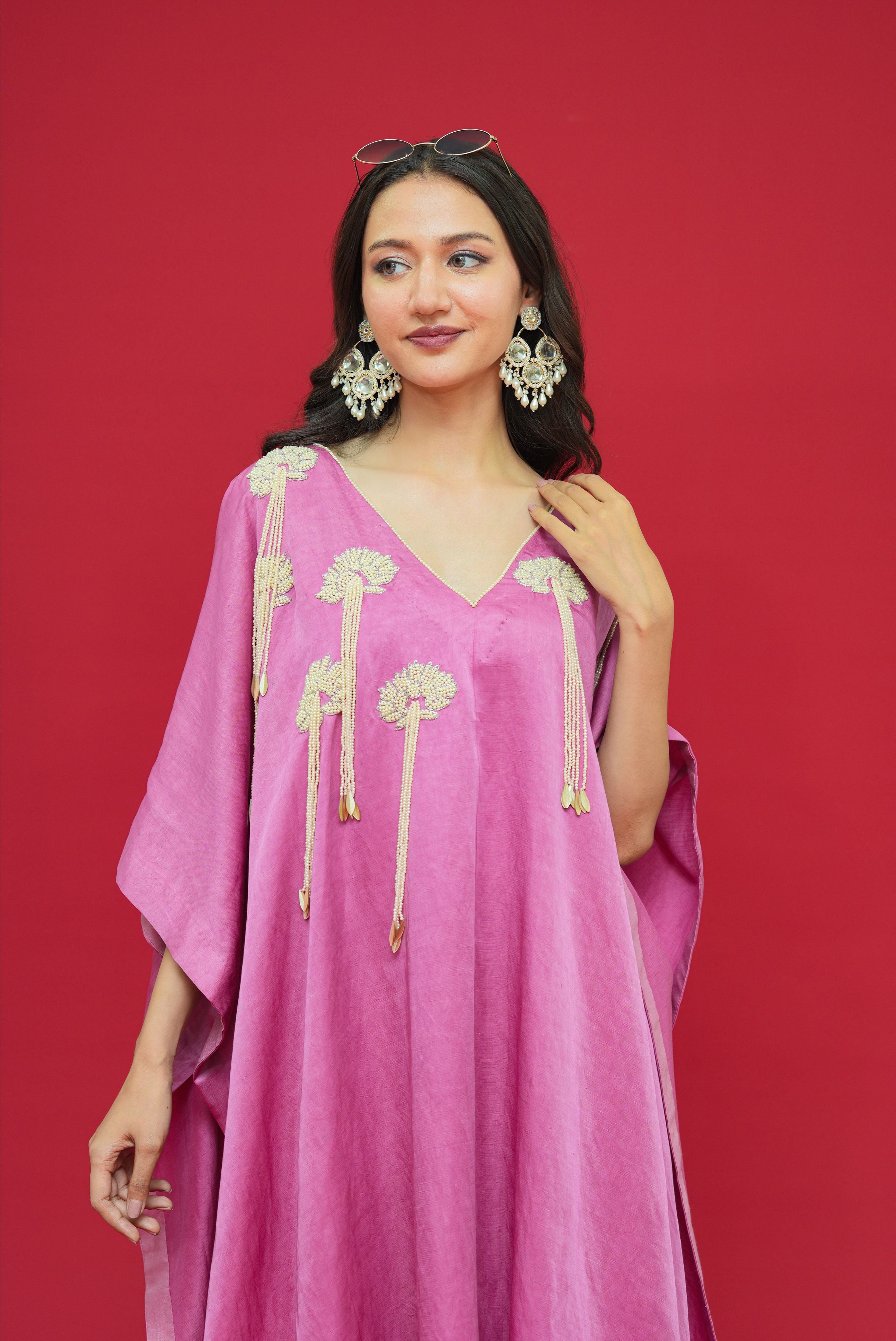 Woman wearing a pink dress with gold embroidery against a red background