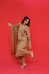 Woman in a beige outfit posing against a red background