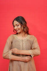 Woman wearing a beige embroidered kurta against a red background