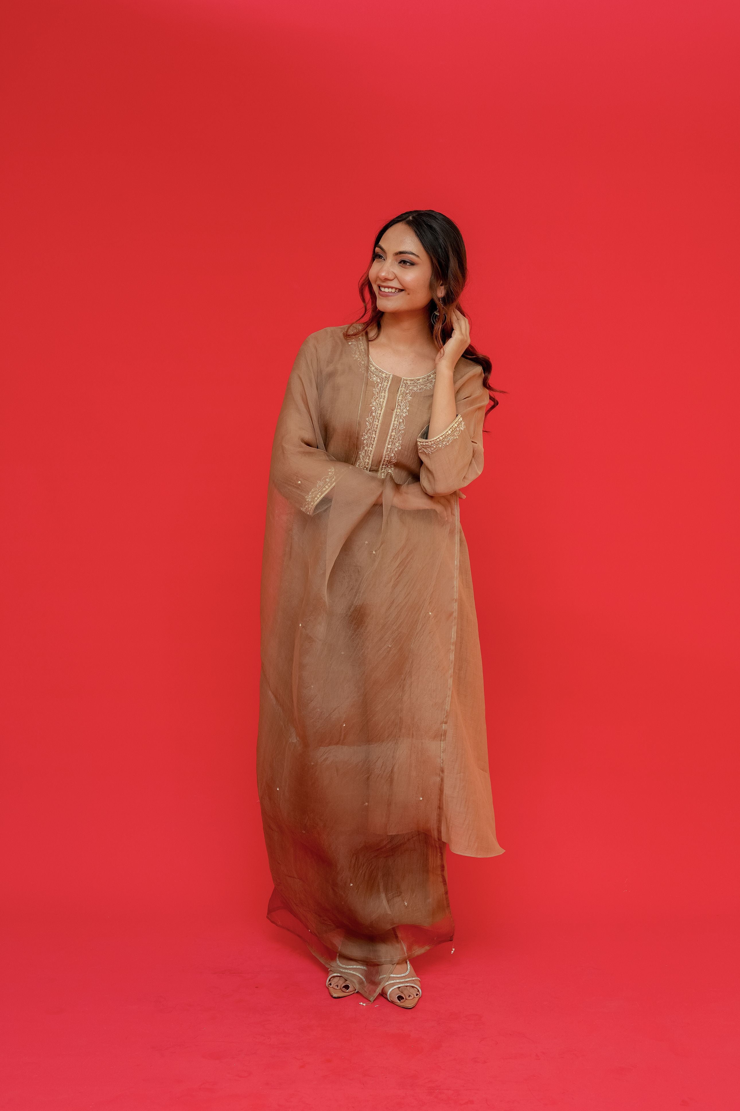 Woman in a beige dress posing against a red background