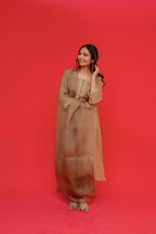 Woman in a beige dress posing against a red background