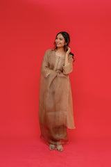 Woman in a beige dress posing against a red background