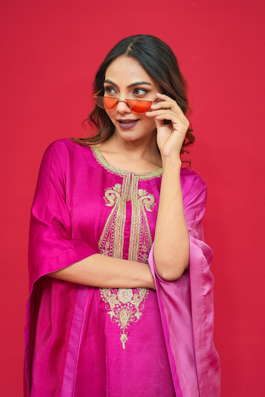 Woman wearing a pink traditional outfit with gold embroidery against a red background