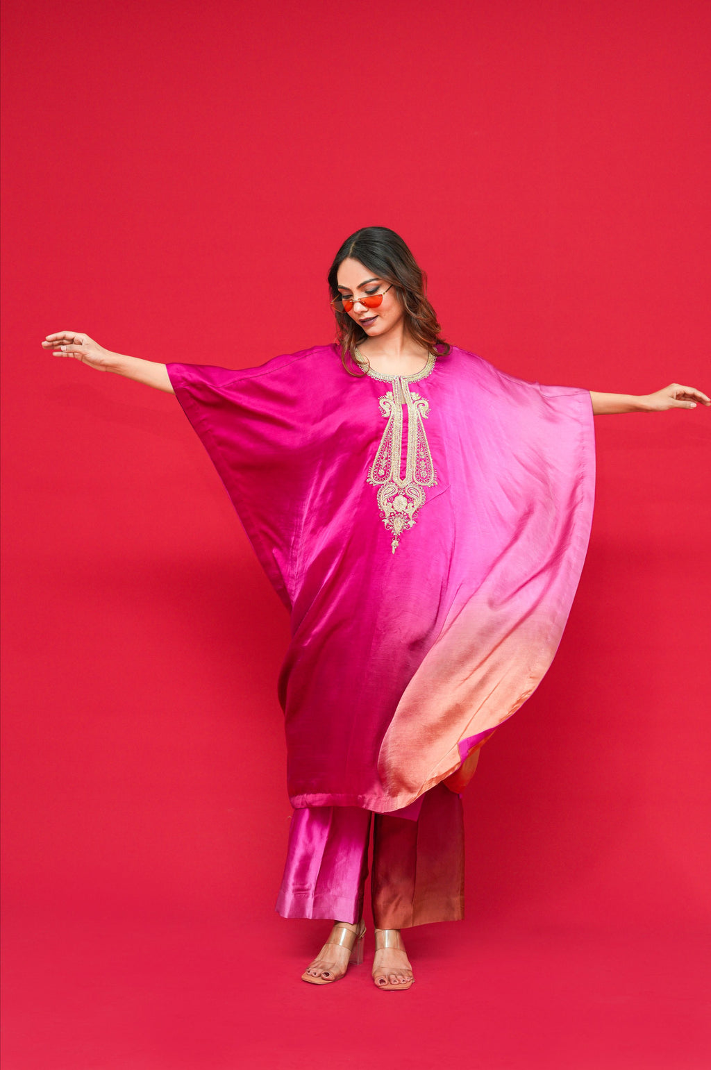 Woman in a pink traditional Nyasa Silk Ombre Kaftan Set with a red background