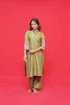 Woman wearing a green dress with floral sleeves against a red background