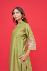 Woman wearing a green dress with floral sleeves against a red background