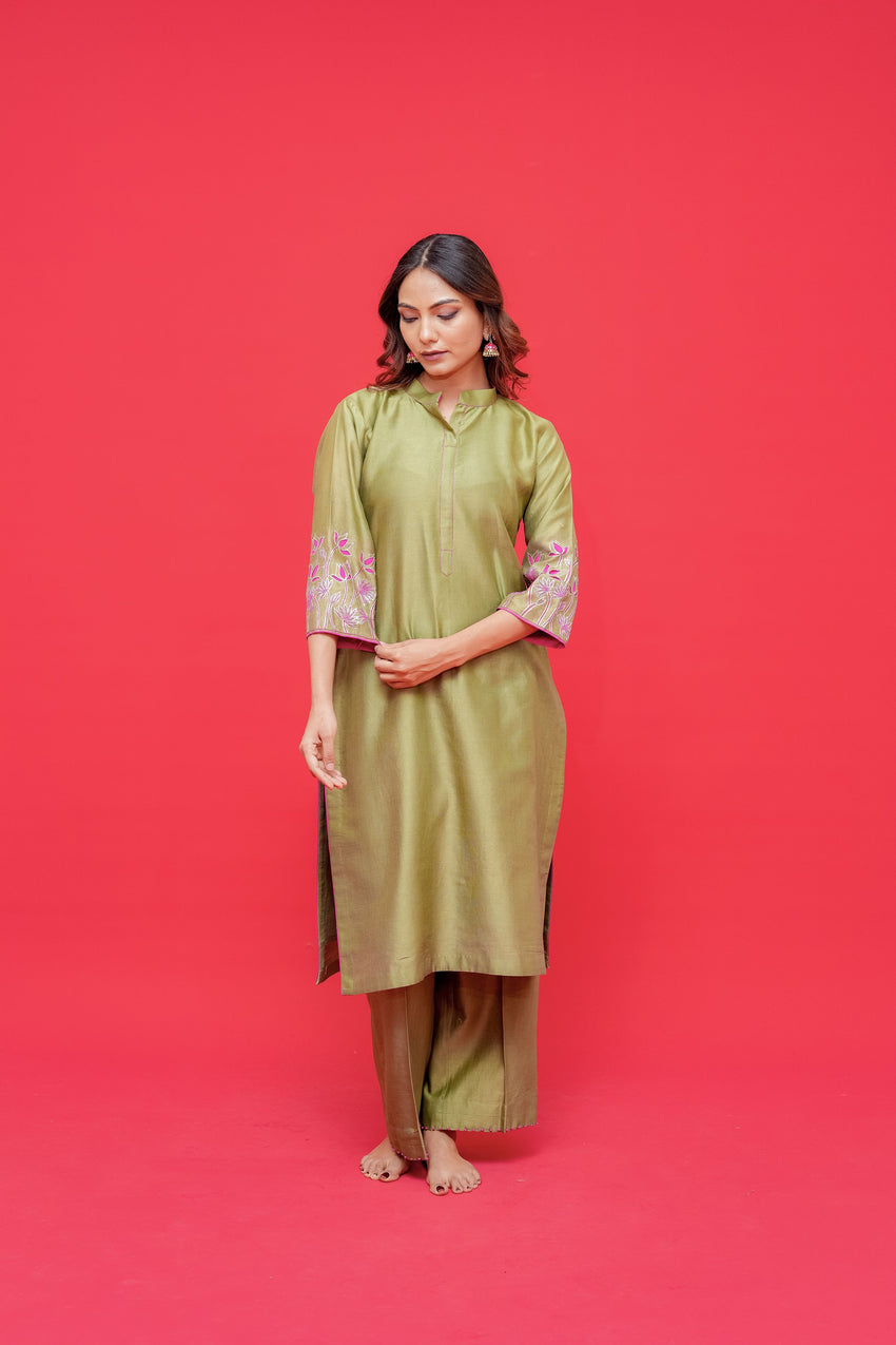 Woman wearing a green dress with floral sleeves against a red background