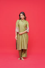 Woman wearing a green dress with floral sleeves against a red background