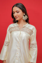Woman wearing a white lace-trimmed blouse against a red background
