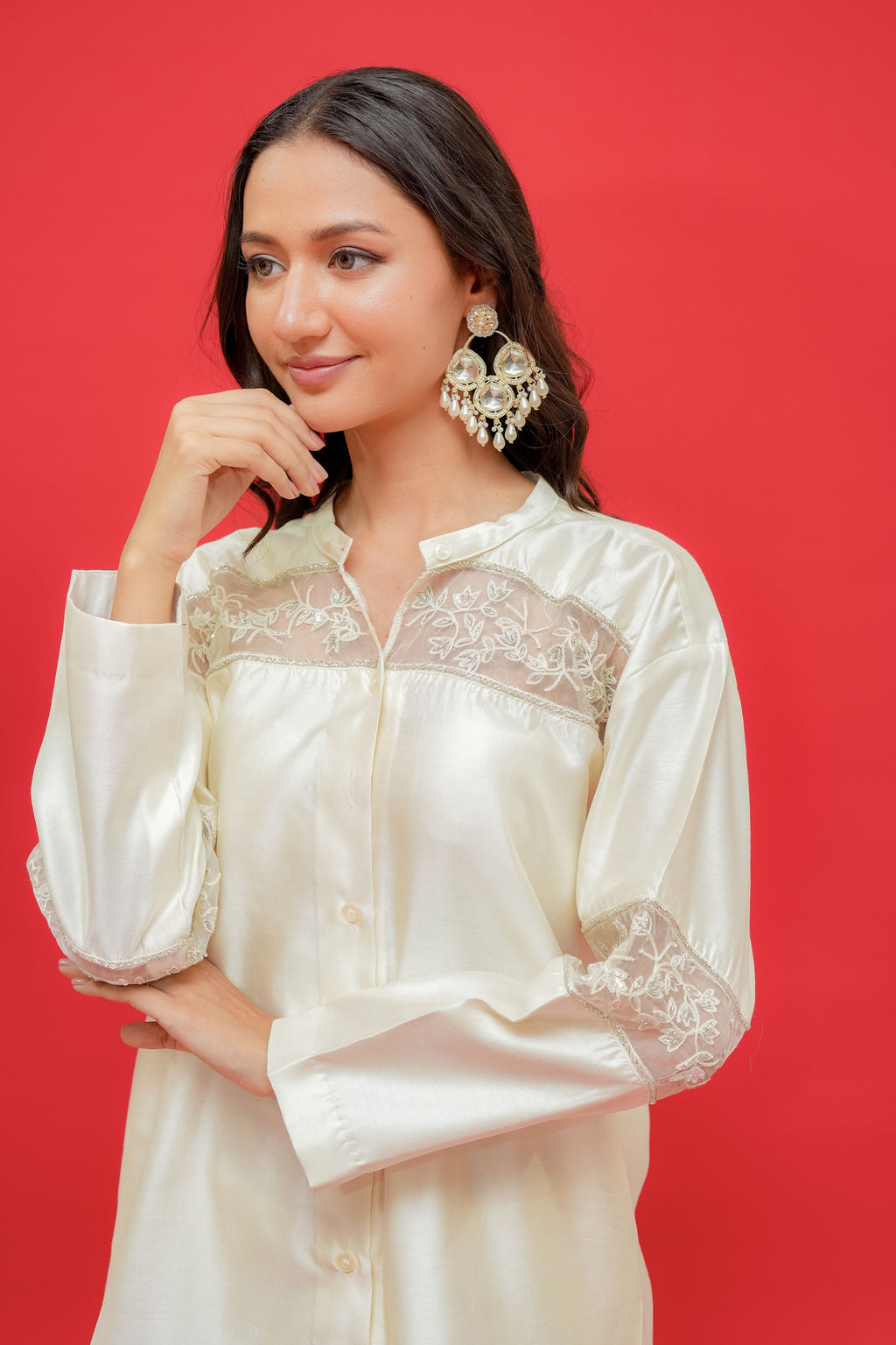 Woman wearing a white lace-trimmed blouse against a red background