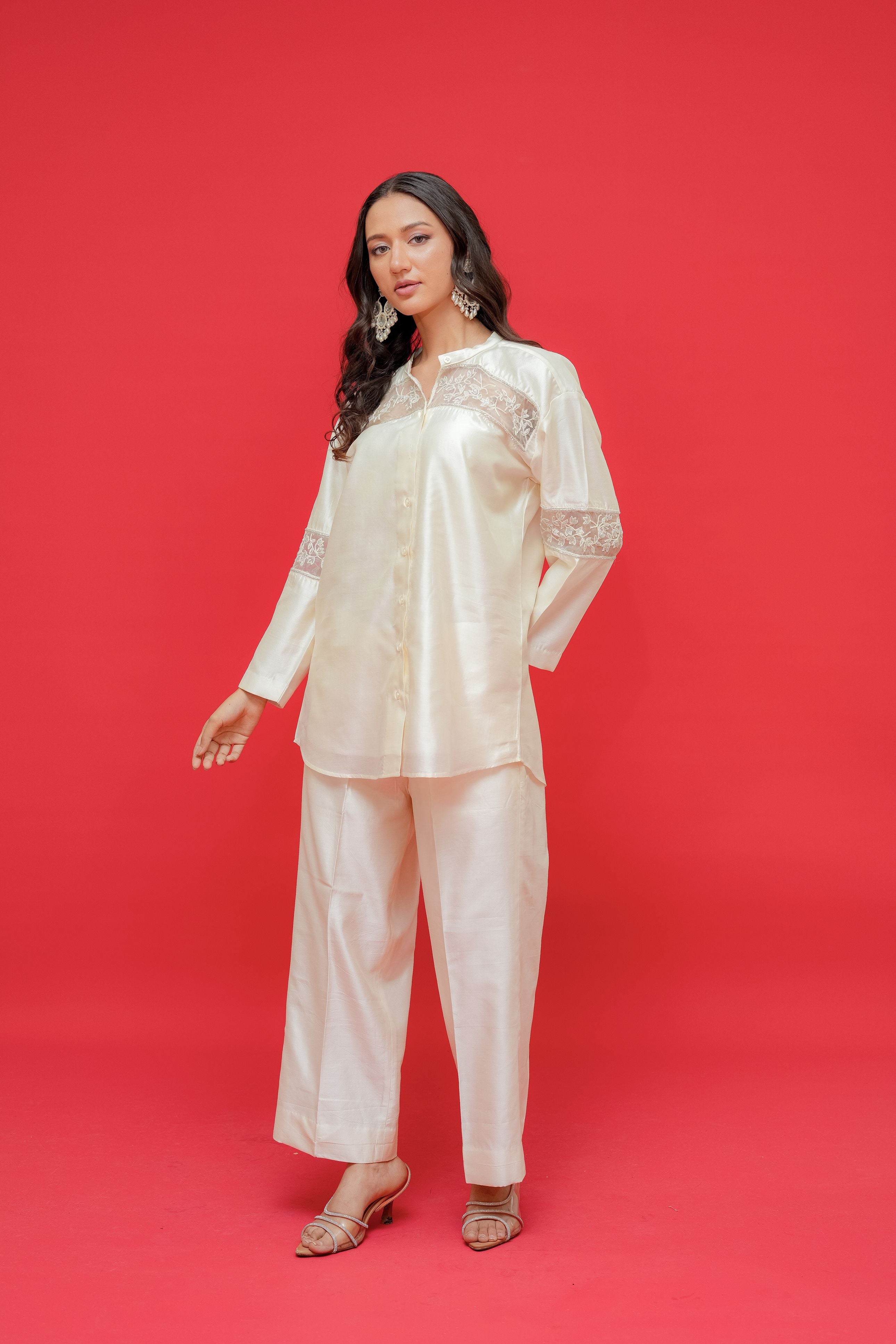 Woman wearing a light pink satin outfit against a red background