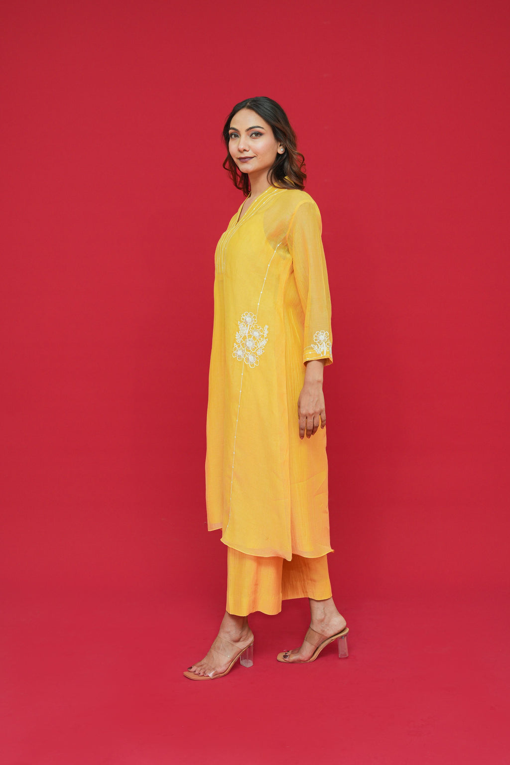 Woman wearing a yellow Pure mul chanderi Thread hand embroidery with floral patterns on a red background