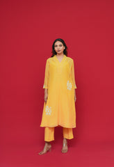 Woman wearing a yellow Pure mul chanderi Thread hand embroidery with floral patterns on a red background