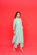 Woman wearing a light blue traditional outfit against a red background