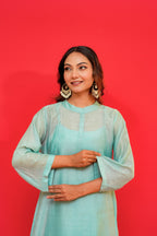 Woman wearing a light blue traditional outfit against a red background