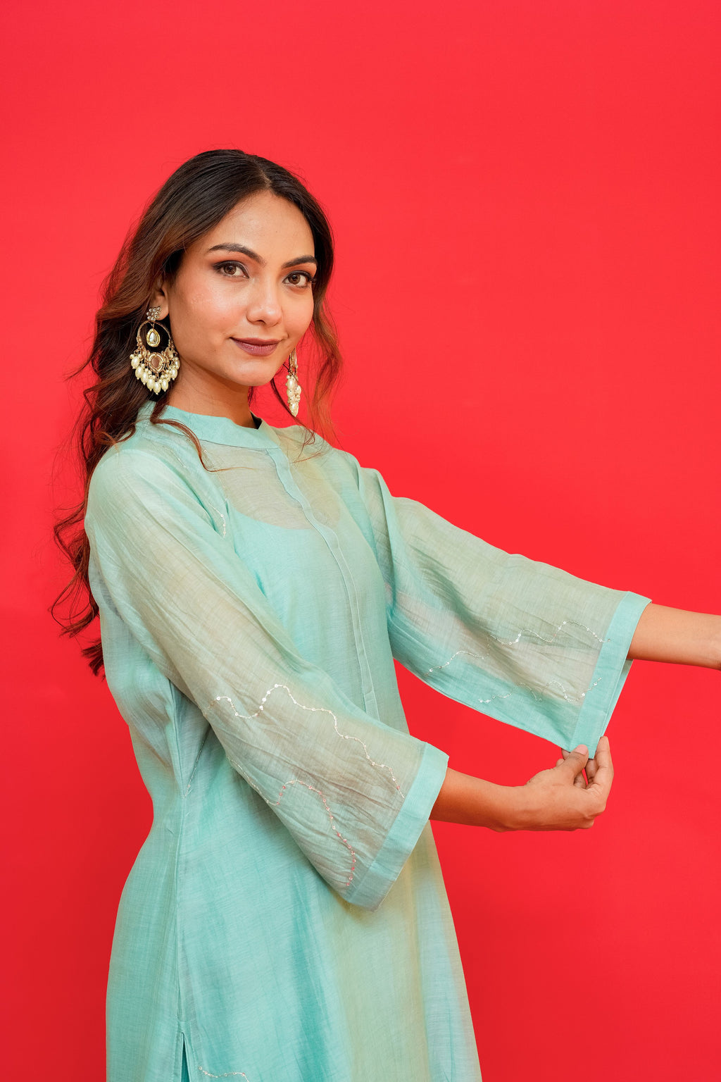 Woman wearing a light blue traditional outfit against a red background