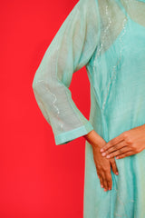 Teal dress with sheer sleeves against a red background