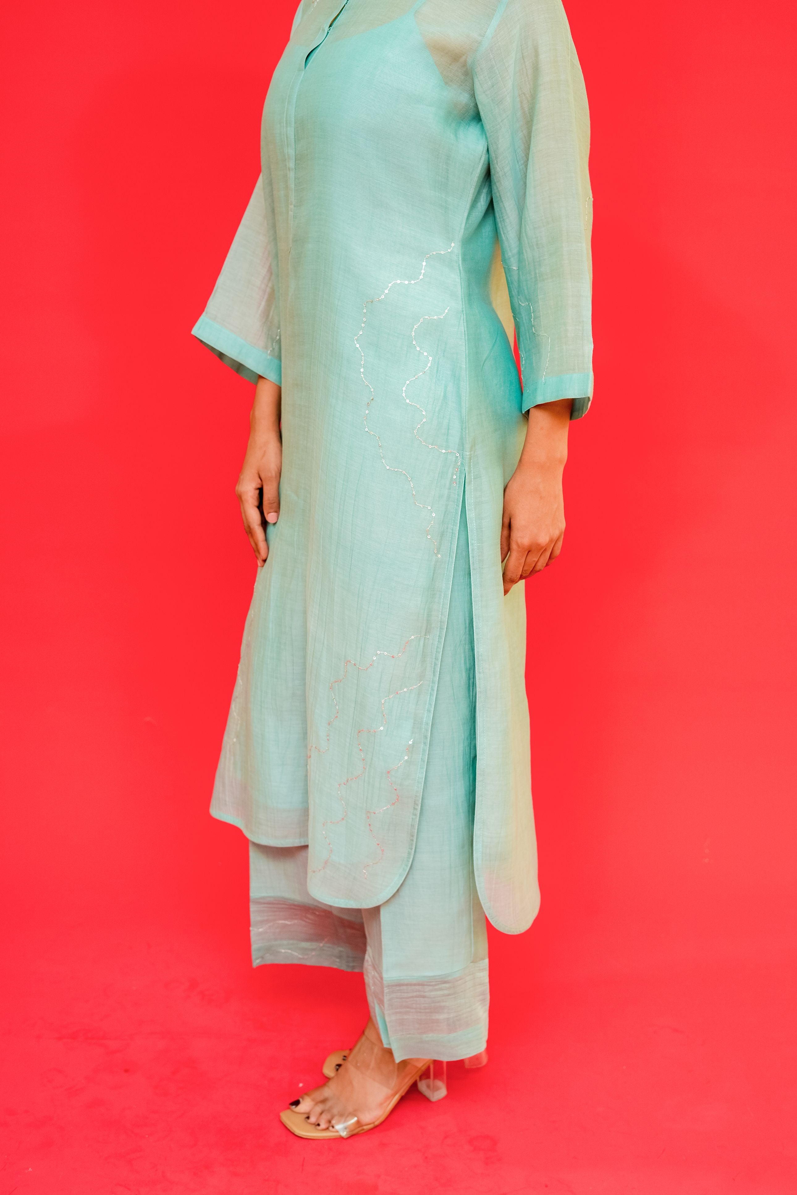 Person wearing a light blue traditional outfit against a red background