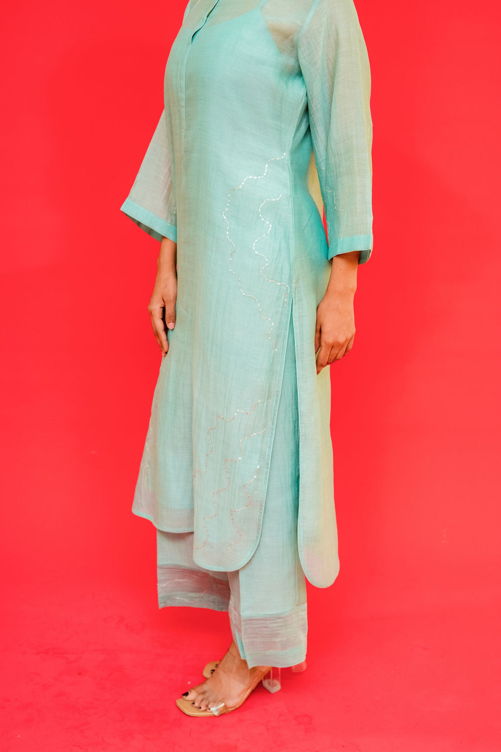 Person wearing a light blue traditional outfit against a red background