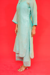 Person wearing a light blue traditional outfit against a red background