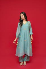 Woman wearing a teal outfit with gold accents on a red background