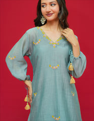 Woman wearing a light blue embroidered dress with yellow details on a red background